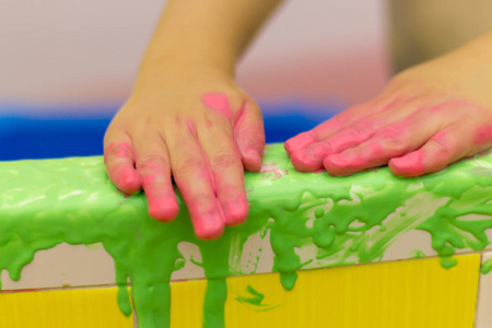 孩子在浴室里玩耍, 用手指画, 浴室在油漆里, 绿色的油漆从墙上流下来. 婴儿的手在粉红色的油漆里