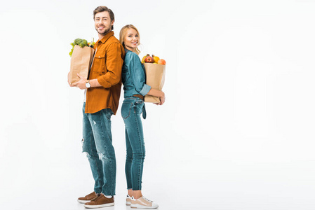 幸福夫妇与购物袋充满产品站在背面查出的白色