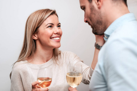 微笑的夫妇喝白葡萄酒和拥抱。特写