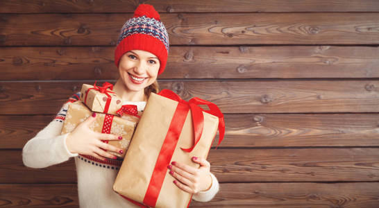 圣诞礼物在冬天帽子木制背上幸福女人