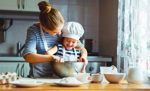 幸福的家庭，在厨房里。母亲和孩子准备面团烘烤