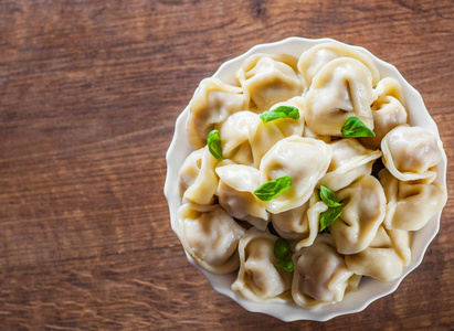 肉饺子俄罗斯的 pelmeni, 拉维奥利与肉在碗在木桌背景