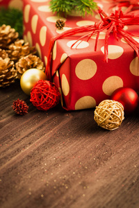 圣诞节和元旦节日装饰, 金球, 五颜六色的冷杉锥和树枝, 木星与礼物包裹在红色纸与金黄圈子在棕色木头背景。复制文本的空间