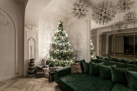 加兰灯泡。圣诞晚会经典的豪华公寓, 装饰圣诞树。客厅大镜子, 绿色沙发, 高窗户, 柱子和灰泥