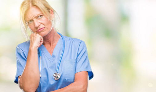 中年金发碧眼的护士医生医生妇女在孤立的背景认为看起来疲惫和厌倦抑郁症问题与交叉手臂