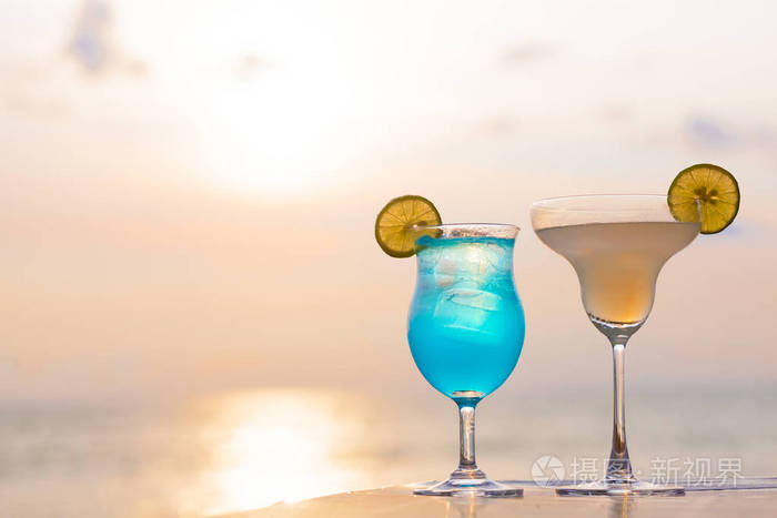 两个完美的鸡尾酒蓝色夏威夷和玛格丽特在日落海滩背景