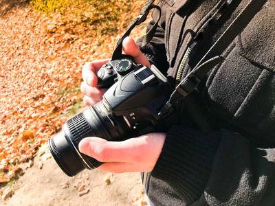 一个大型的黑色现代数字镜子专业相机在摄影师手中。一个人摄影师调整相机