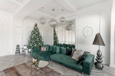 圣诞节的早晨。经典的豪华公寓, 装饰圣诞树。客厅大镜子, 绿色沙发, 高窗户, 柱子和灰泥