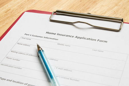 家庭保险申请表与红木制的桌子上的文件