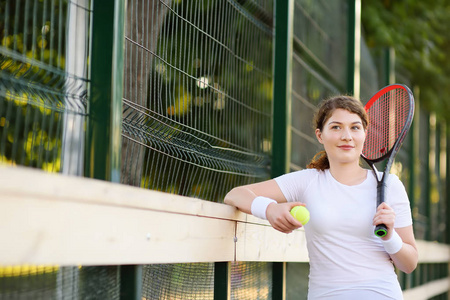 年轻女子网球运动员与网球和球拍准备发球。女孩网球场