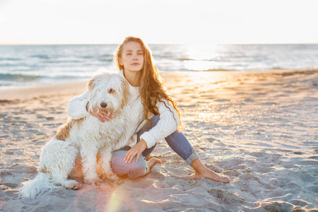 一个年轻美丽的妇女的画像与狗在海滩上