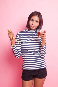 年轻的亚洲妇女与蕃茄汁和测量磁带在粉红色背景
