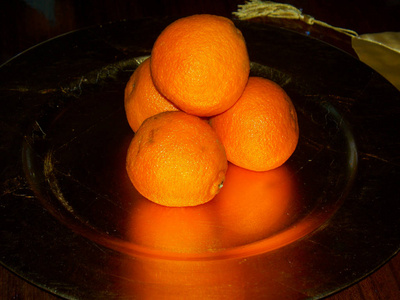 整个橙子堆积在一个金色的盘子里
