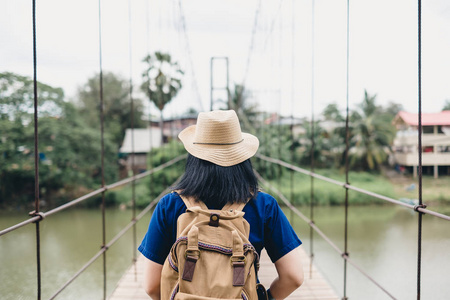 旅行亚洲妇女与背包在脚桥过河在农村, 暑假旅行