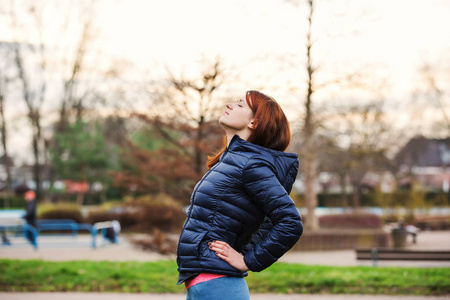 年轻女人在听音乐的城市公园延伸户外