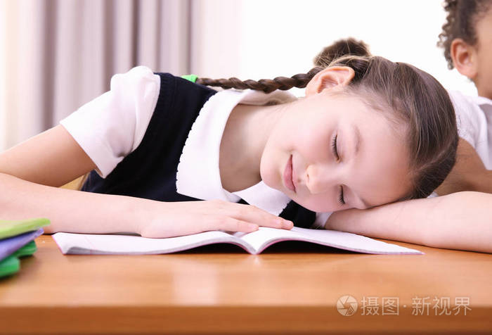 在教室里睡在课桌上的疲倦的小学生画像