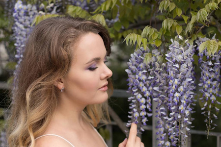 紫藤。丁香花附近一个年轻美丽的女人的肖像。温暖的春天