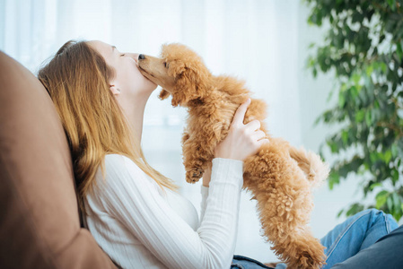 与一只狗在家里的沙发上休息的年轻女孩