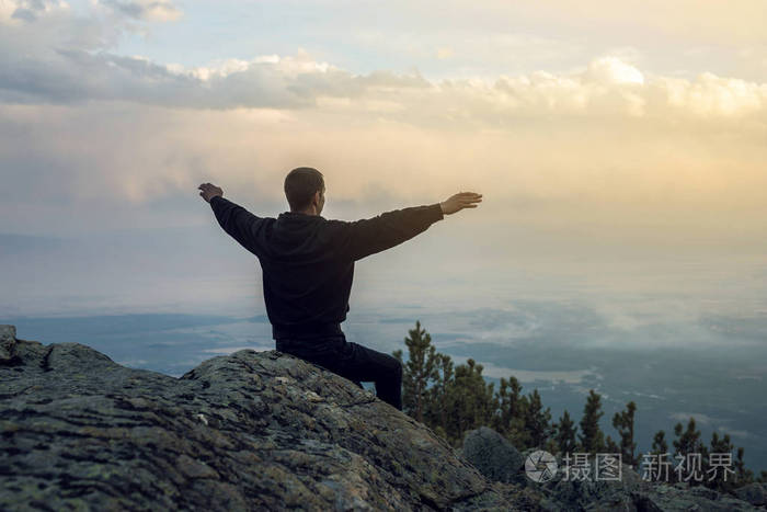 男人正坐在一个石头的山坡上,手查看该视图从高地和享有自由
