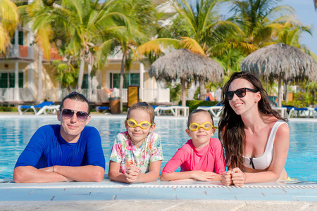 年轻的家庭，两个孩子享受暑假在室外游泳池