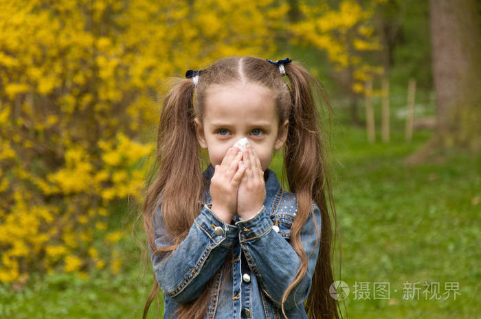 这个女孩有一个流鼻涕的鼻子.花花粉过敏.这个女孩是