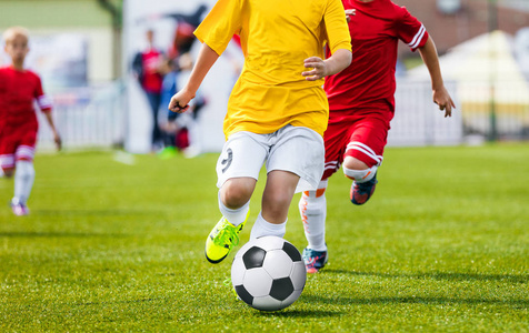 运行青年足球足球运动员。男孩踢足球比赛。儿童足球运动员追球。孩子们运动决斗