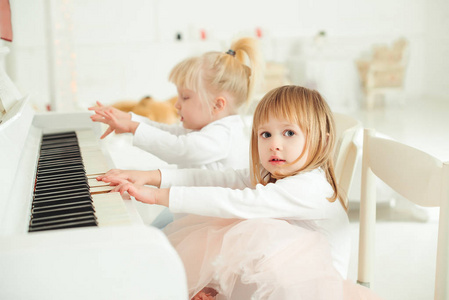 两个可爱的小女孩弹钢琴的一个摄影棚里