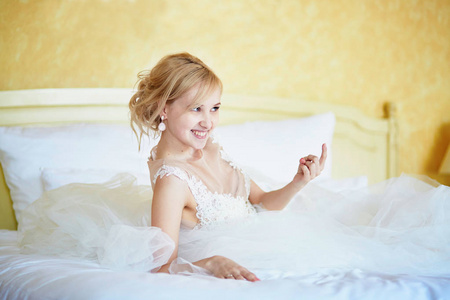性格开朗年轻的新娘穿着婚纱时在酒店房间里