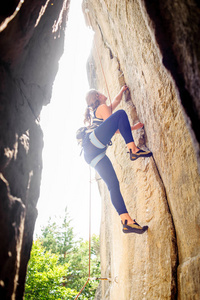 用根绳子爬上岩壁的女性登山者