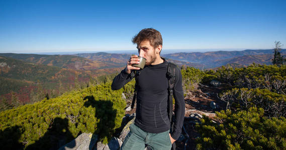 年轻健康男性的徒步旅行者喝茶的肖像