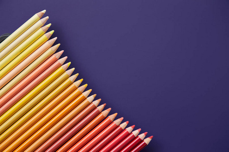 紫色背景上的彩色的铅笔。美丽的组成