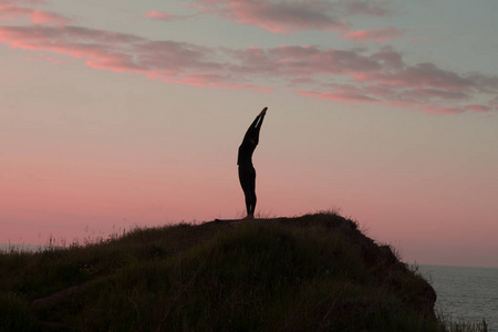 适合女人做瑜伽伸展运动户外在美丽的高山景观。女性的海和日出或日落背景培训 asans 岩石上。女人的瑜伽体式的剪影
