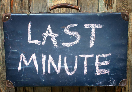 最后一分钟旅游概念与旧手提箱木制背景