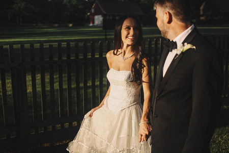幸福的新娘在新郎看起来和他手牵手散步的时候