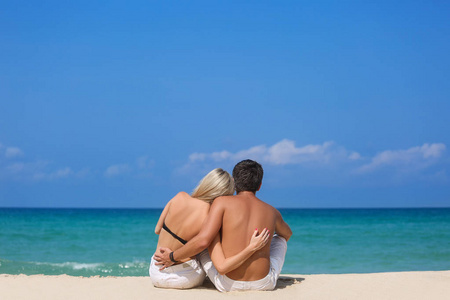浪漫的情侣坐在沙滩上，欣赏美丽的海景，侧视图，花时间在一起，夏天度假概念