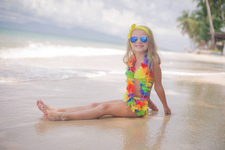 幸福的小女孩微笑，在海边沙滩上的墨镜