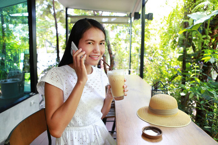 年轻的亚裔女子，坐在咖啡馆里使用智能手机