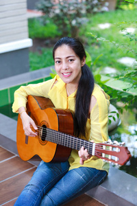 亚洲女人弹古典吉他，室外白天与明亮的阳光下