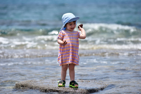蹒跚学步婴儿玩和在海水开心