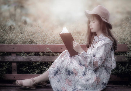 年轻女人戴着一顶帽子，在公园里读书