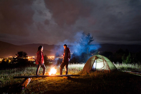 晚上露营。男人和女人站在篝火旁