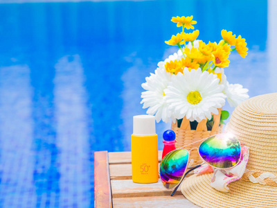 与夏天的帽子，防晒霜太阳镜  防晒霜和游泳池旁的鲜花。假期和松弛，夏天旅游概念