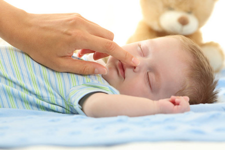 母亲的手抚摸着熟睡的婴儿鼻子