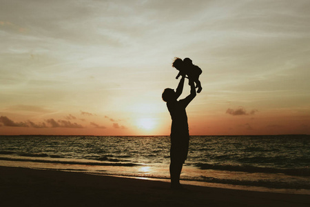 父亲和小宝宝玩在日落时的剪影