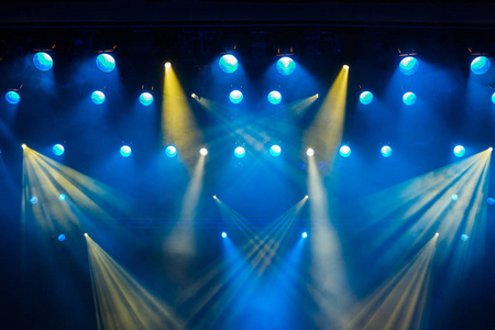 在舞台上的戏剧演出期间的照明设备。透过烟雾聚光灯从光线。蓝色和黄色的光线