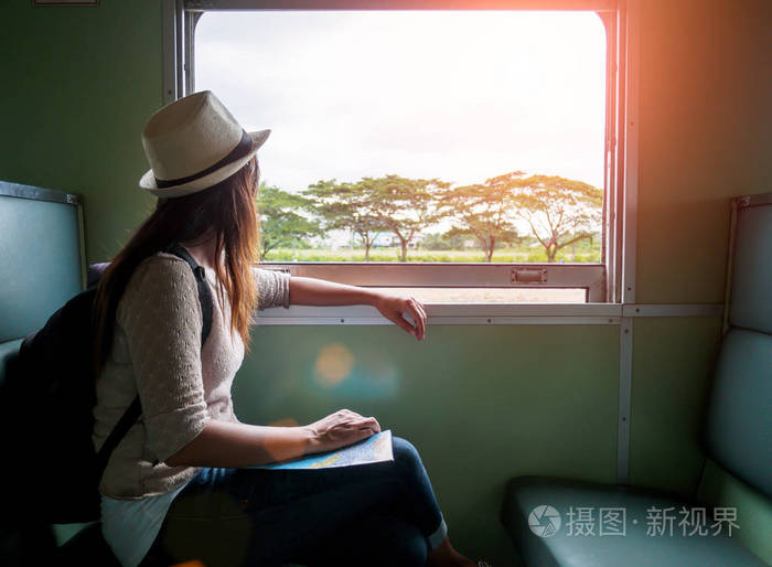 年轻漂亮的女人坐坐在窗边看着窗外的经典火车旅行.度假和旅游的概念