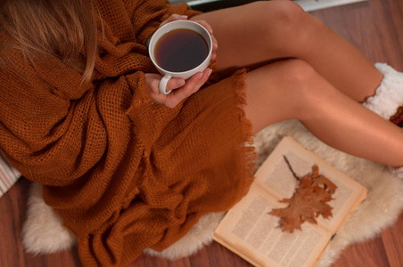 裹在温暖的格子毛毯，喝热茶和在秋天看书的女人