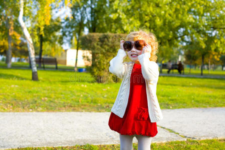 一个小女孩在户外戴着大太阳镜玩耍的画像