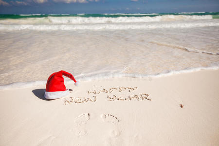 白色沙滩上的圣诞帽和新年快乐