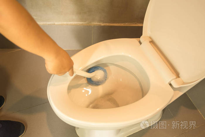 女人清洗马桶使用蓝色画笔的手